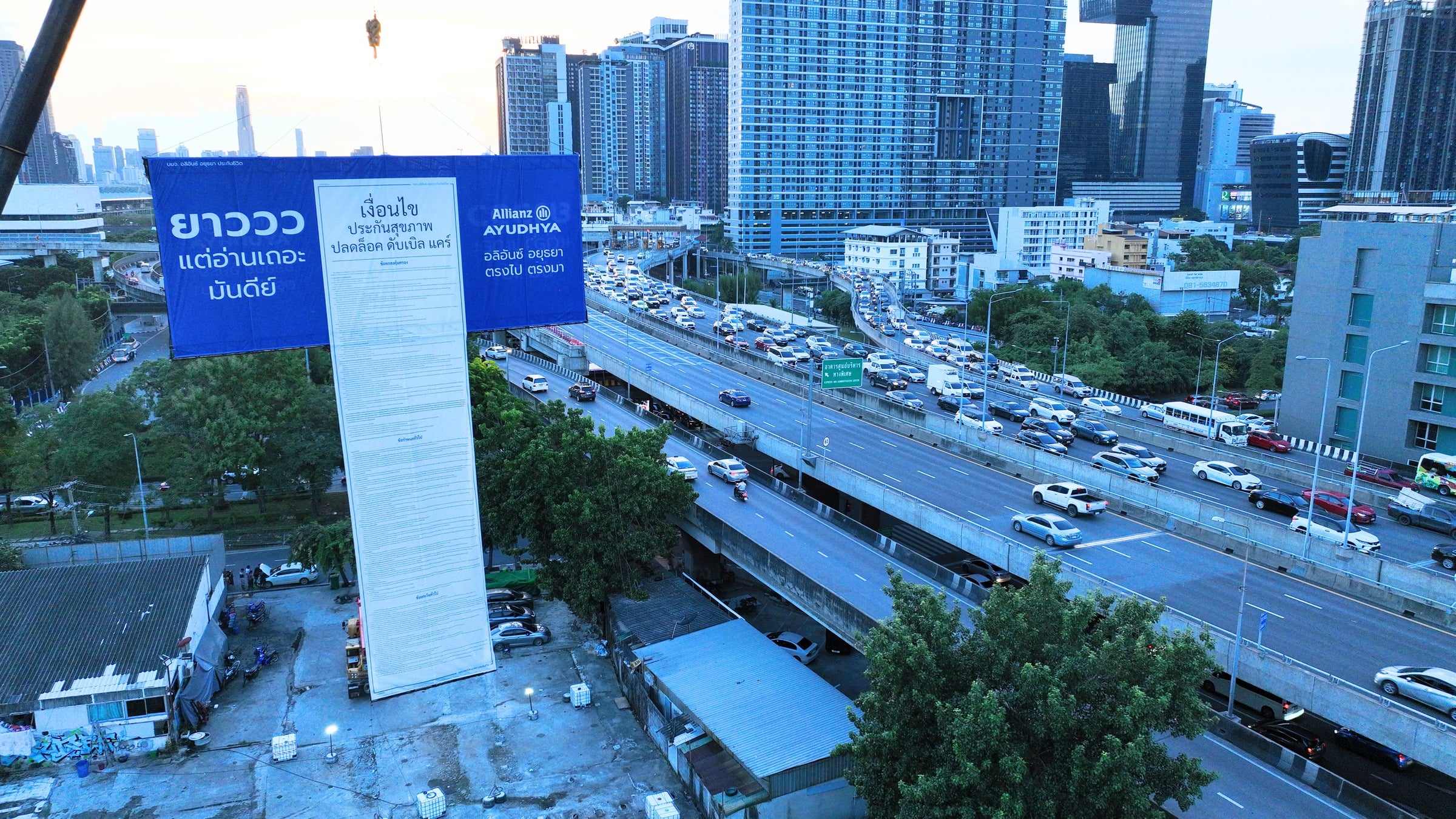 An Allianz Ayudhya mega-banner hanging above a Bangkok expressway, produced and installed by Bigger Ads